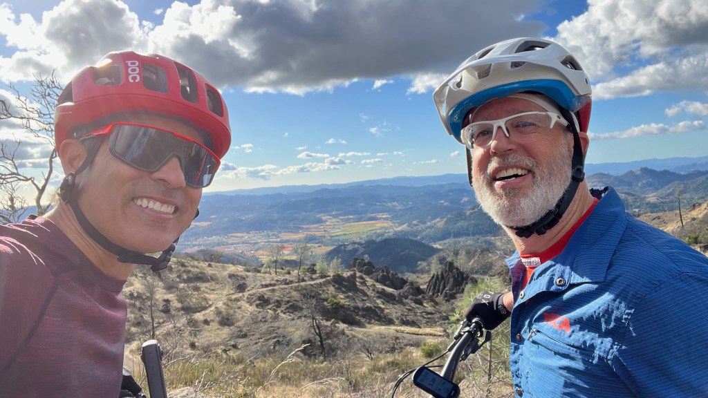 Photo of Gerardo with rider on top of mountain bike trail